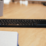 Clavier multimédia noir, azerty, posé sur un bureau.