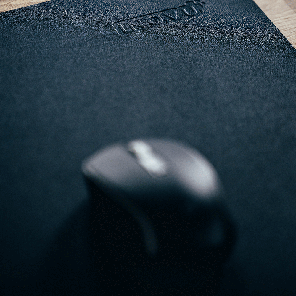 Grand zoom sur un tapis de souris noir avec une souris noire posée dessus.