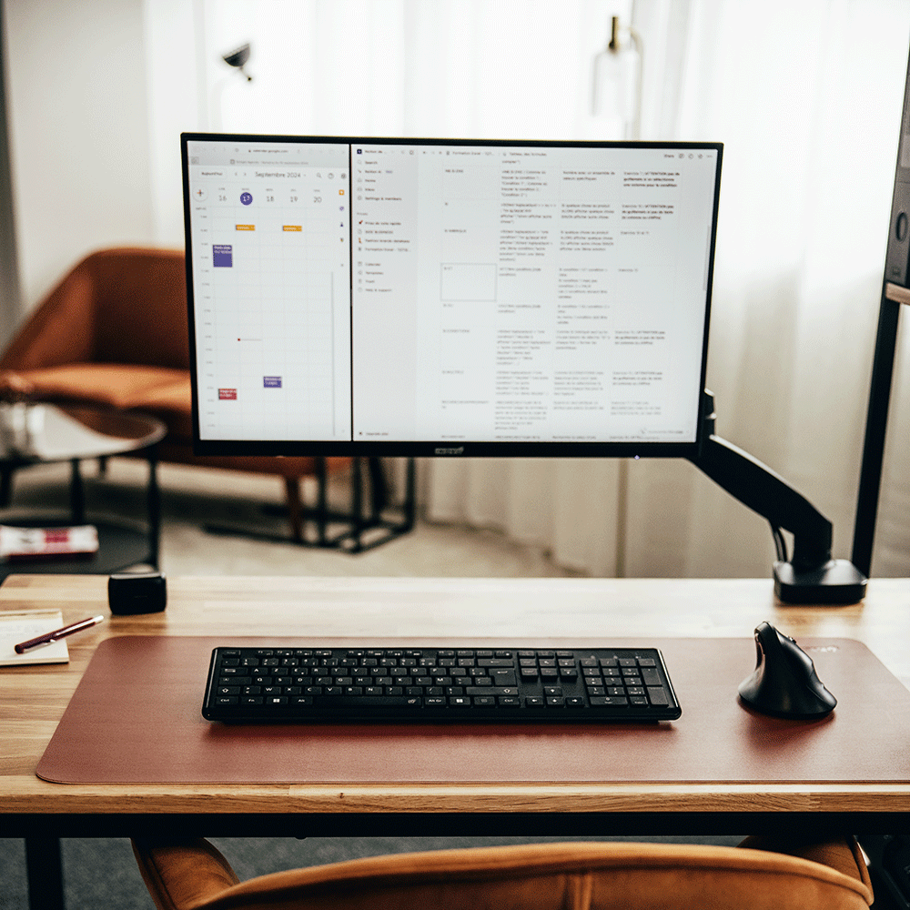 Tapis de souris marron disposé sur un bureau en bois, avec un clavier noir, une souris et un écran d'ordinateur.