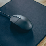 Souris filaire noire posée sur un tapis de bureau bleu, avec un design professionnel.