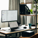 Écran installé sur un bureau avec ordinateur portable et accessoires de travail.